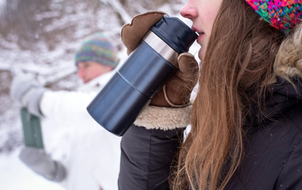 A woman drinks from a Stanley mug