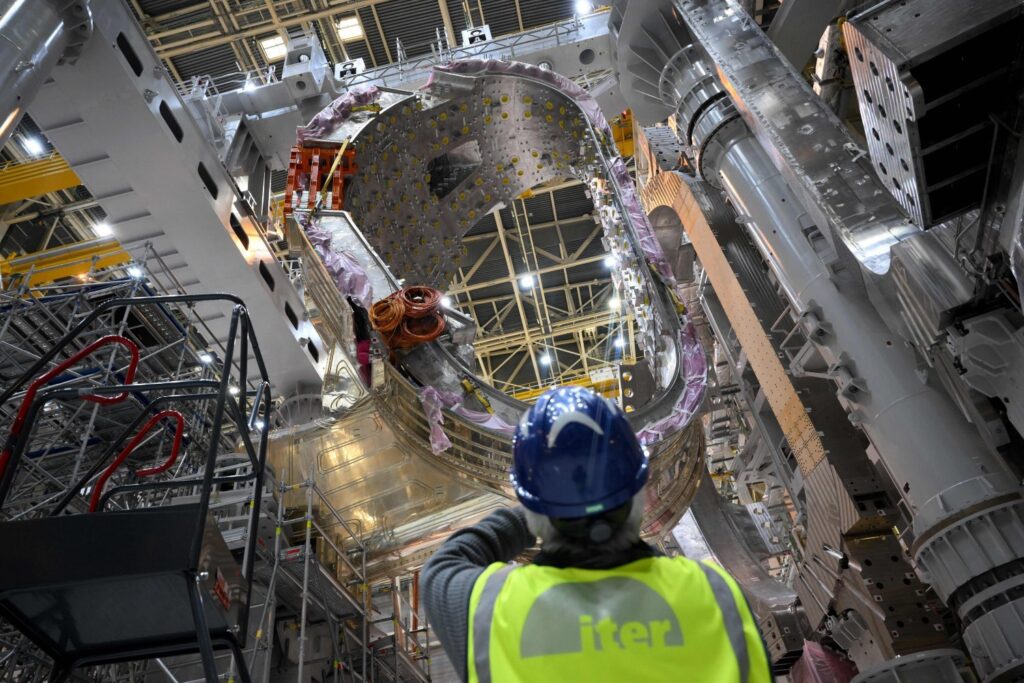 A man takes a picture of a module being assembled at the international nuclear fusion project