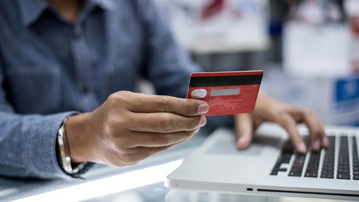 Person holding a credit card over a laptop