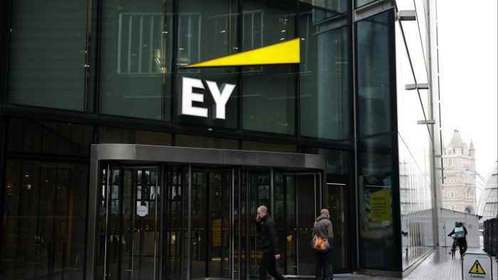 Pedestrians walk past the EY office in London