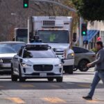 A white, autonomous Waymo car on the road in San Francisco.