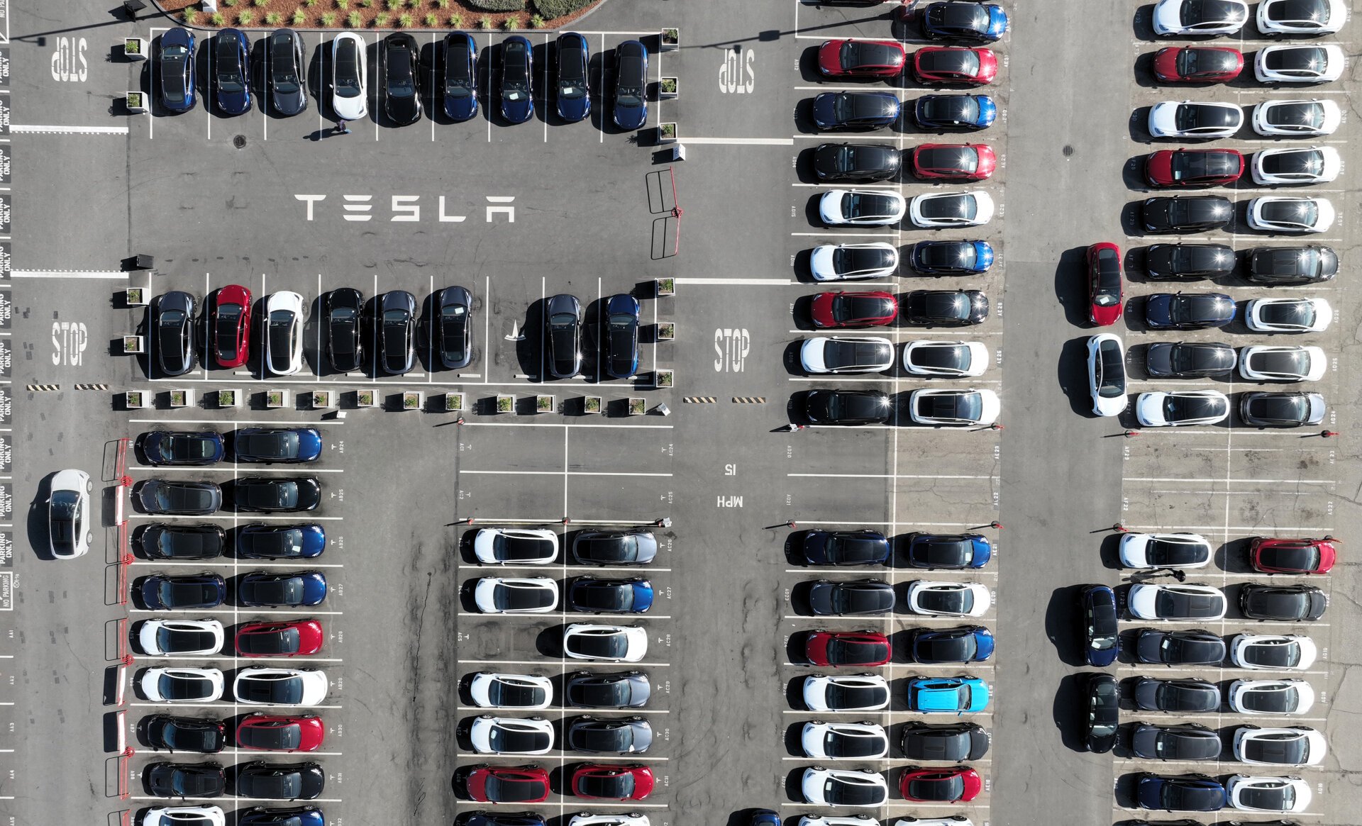 An aerial view of Tesla cars sitting in a parking lot