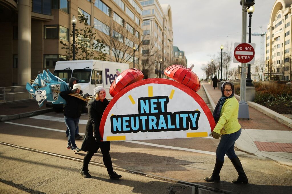 Protesters carry a large prop clock with the words "net neutrality" written on it.