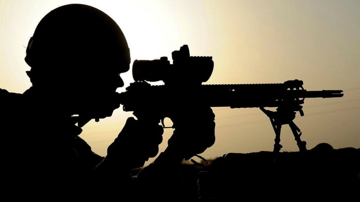 Silhouette of soldier firing rifle