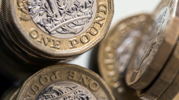 British one pound coins stand stacked in this arranged photograph