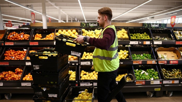 A employee arranges produce inside a Sainsbury’s supermarket in Richmond