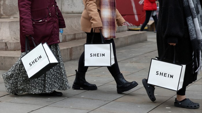 Shoppers carry bags with promotional merchandise as they visit fashion retailer Shein’s Christmas bus tour, in Manchester, England in December 2024