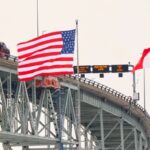 The US and Canadian flags fly on the US side of the St Clair River near the Bluewater Bridge border crossing between Sarnia, Ontario and Port Huron, Michigan.