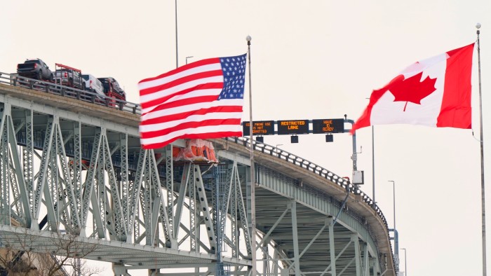 The US and Canadian flags fly on the US side of the St Clair River near the Bluewater Bridge border crossing between Sarnia, Ontario and Port Huron, Michigan.