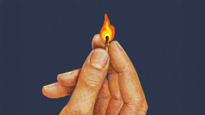 A hand holds a burning match