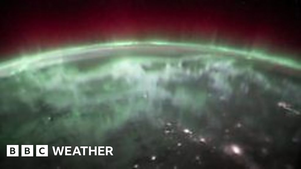 A view of the earth from space with red and green aurora