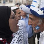 A pro-Palestinian woman wearing a headscarf shouts at a pro-Israeli man wearing a blue and white hat bearing the Israeli flag