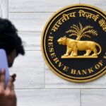 man on mobile phone walking past Reserve Bank of India sign