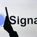 An image of a woman holding a cell phone in front of the Signal logo displayed on a computer screen, on April 29, 2024, in Edmonton, Canada.