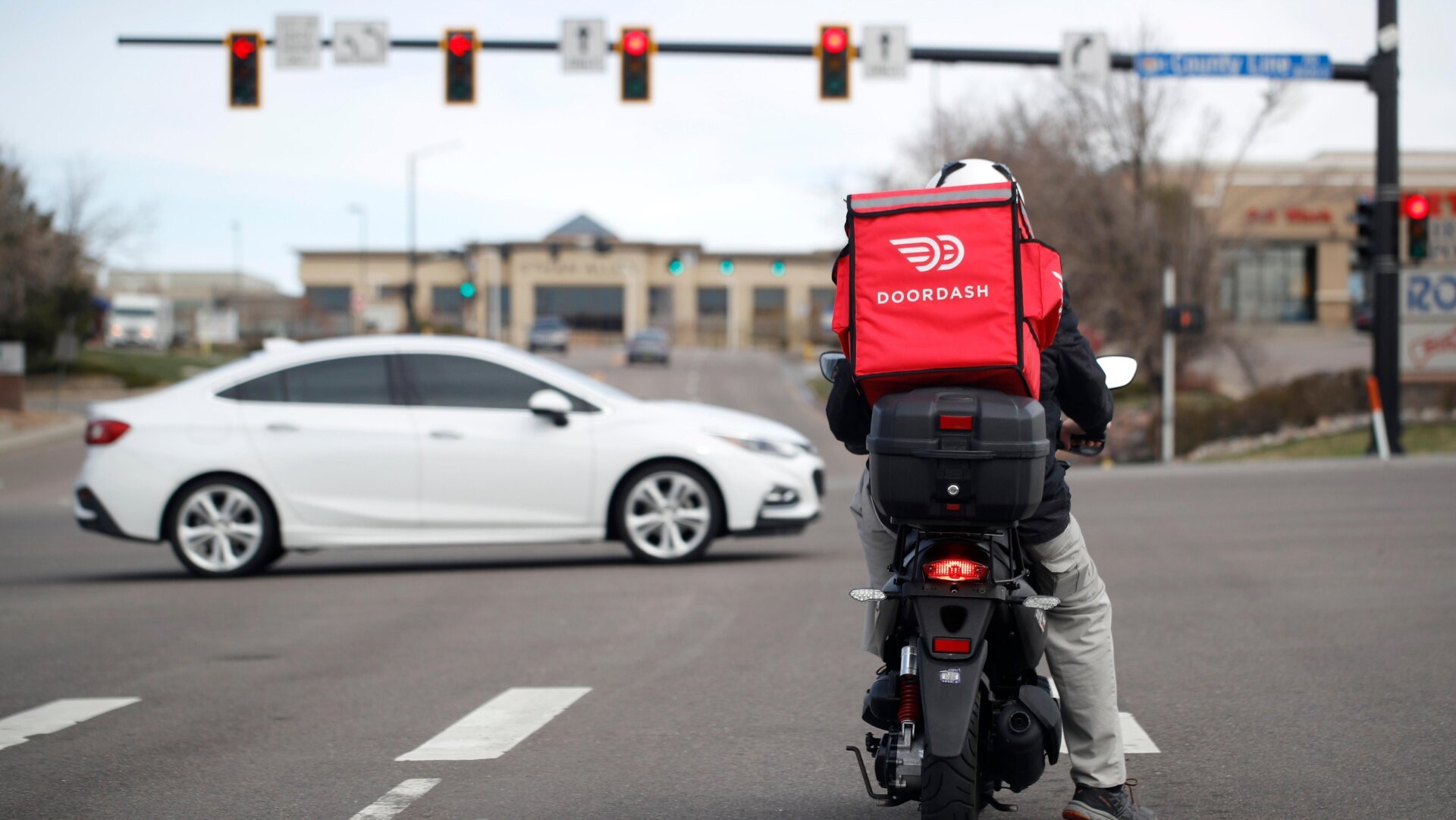 DoorDash driver on a motorbike waits at a stoplight.