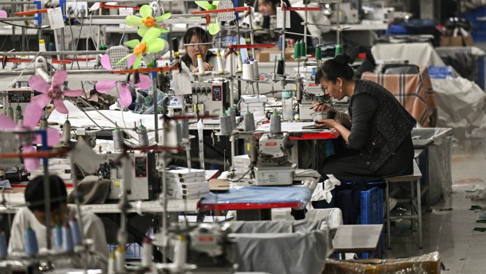 A woman sits at a workbench in a clothing sewing workshop in Guangzhou, China