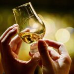 Close-up of someone holding whisky in a small glass