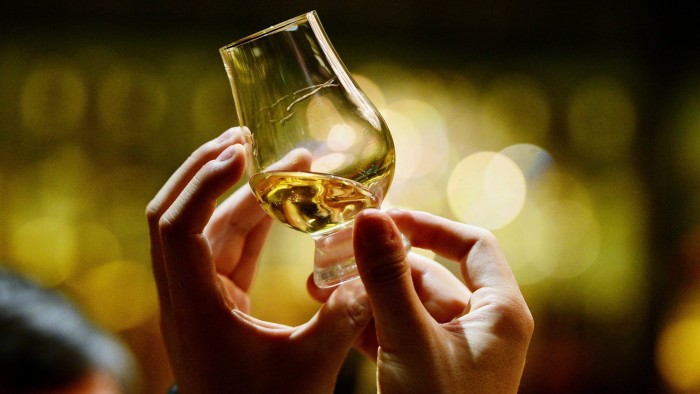 Close-up of someone holding whisky in a small glass