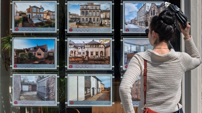 A young woman looking at properties for sale in the window of an estate agents in Edinburgh