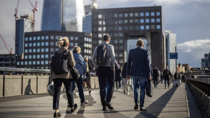 Office workers walk across London Bridge in the early evening