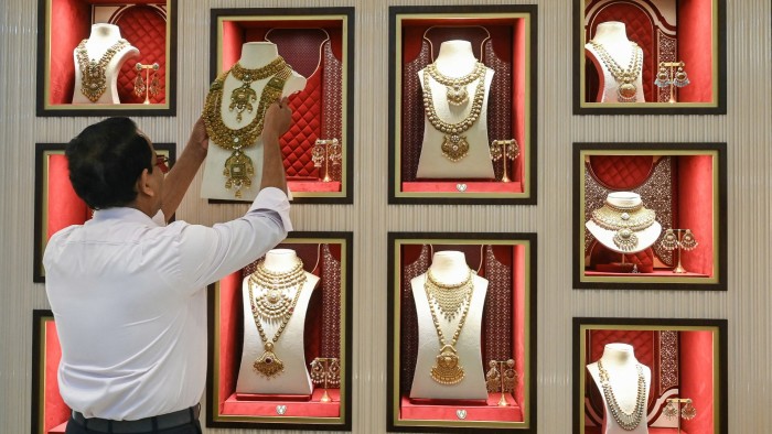 An employee arranges gold jewellery kept for display at a store