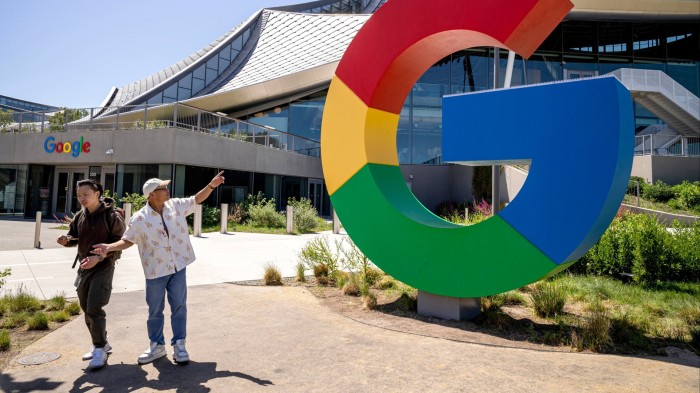 Two men standing in front of a Google sign