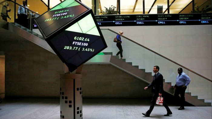 People walk through the lobby of the London Stock Exchange in London