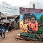 Children stand near a grafitti mural in Kibera