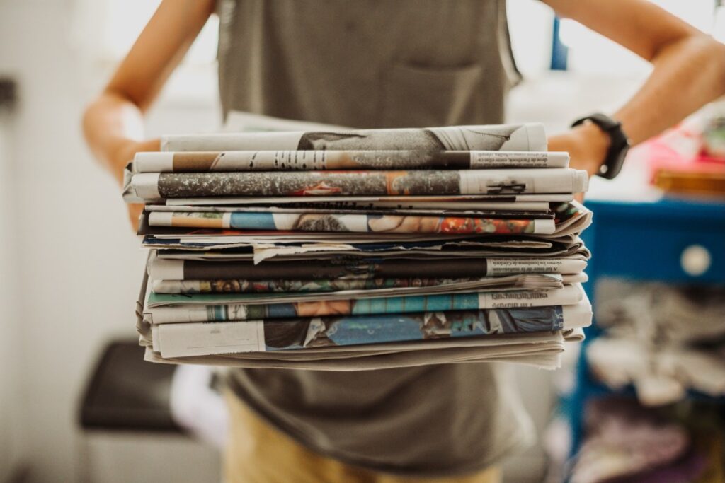 a person carrying a stack of newspapers in front of them