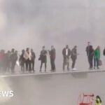 Passengers seen on wing of plane after jet catches fire