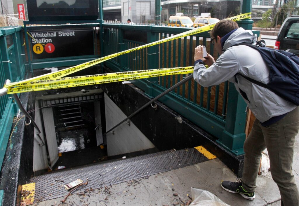 A man uses his mobile phone to photograph a closed subway station.