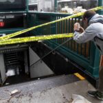 A man uses his mobile phone to photograph a closed subway station.