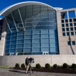 A journalist with a video camera pointed at the exterior of the US Institute of Peace building