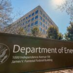 The U.S. Department of Energy building is seen behind a sign marking the location of the agency's headquarters.