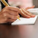 close up on hands writing a cheque