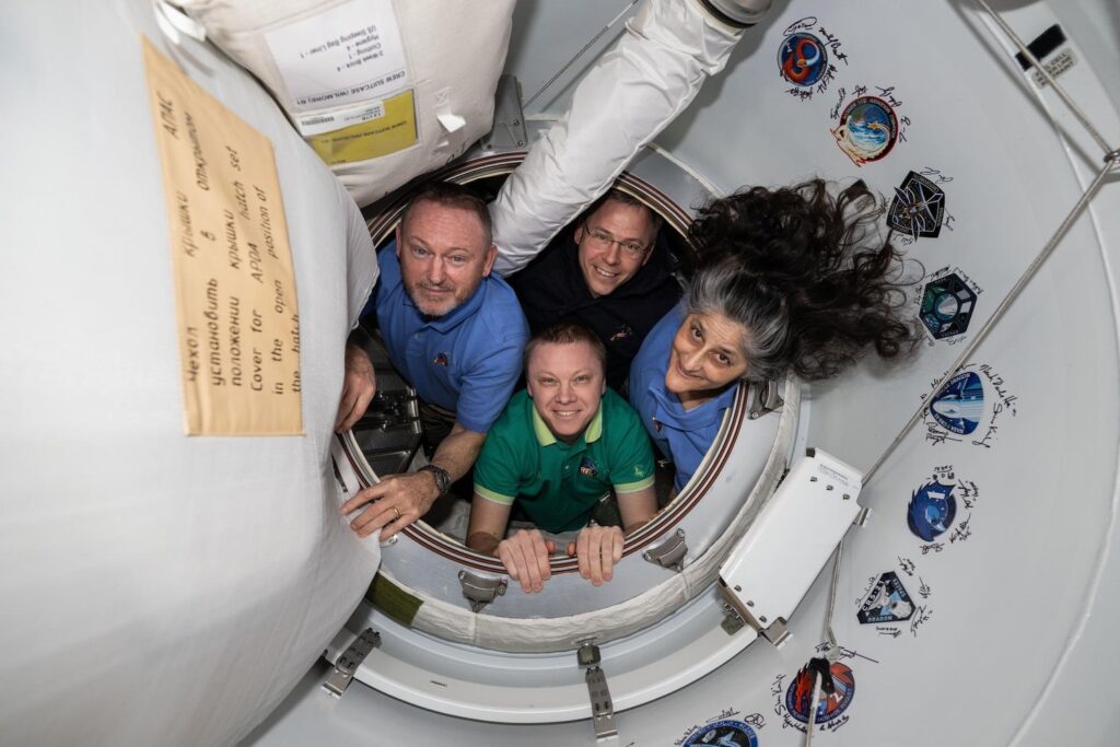 NASA’s SpaceX Crew-9 members pose together for a portrait inside the vestibule between the International Space Station and the SpaceX Dragon crew spacecraft. Clockwise from left, are NASA astronauts Butch Wilmore, Nick Hague, and Suni Williams, and Roscosmos cosmonaut Aleksandr Gorbunov.