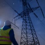 High voltage engineer working on power lines at night.