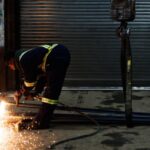 A worker at North York Iron in Toronto is cutting a piece of steel with a torch