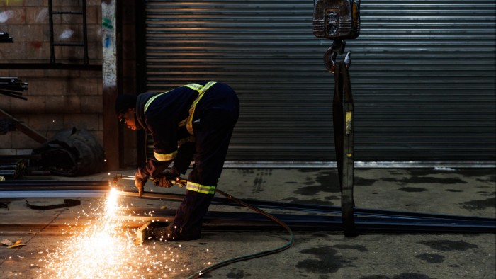 A worker at North York Iron in Toronto is cutting a piece of steel with a torch