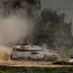 An Israeli tank manoeuvres on the Israeli side of the border between Israel and Gaza