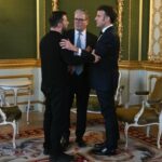 Volodymyr Zelenskyy, Keir Starmer, and Emmanuel Macron stand together in conversation