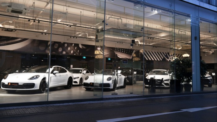 White cars are displayed in a well-lit, modern glass-front Vincar showroom