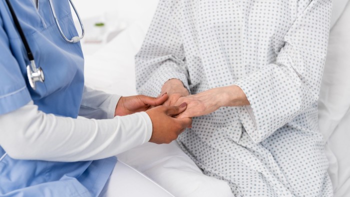 A nurse holds a patient’s hand