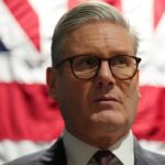 Keir Starmer stands in front of a Union Jack flag during a tour of Palantir Technologies headquarters