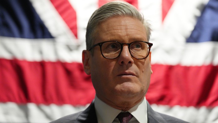 Keir Starmer stands in front of a Union Jack flag during a tour of Palantir Technologies headquarters