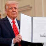 President Donald Trump holds up a signed executive order