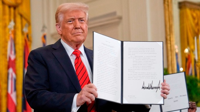 President Donald Trump holds up a signed executive order