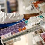 A pharmacist looks for medication on a pharmacy’s shelves in London