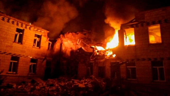 Flames and thick smoke engulf a building in Krasnopillia, Sumy region, Ukraine on March 19 2025. The structure is heavily damaged, with fire visible through the windows and debris scattered in the foreground.