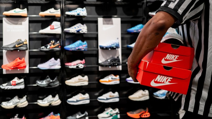 Store employee holds boxes of Nike shoes